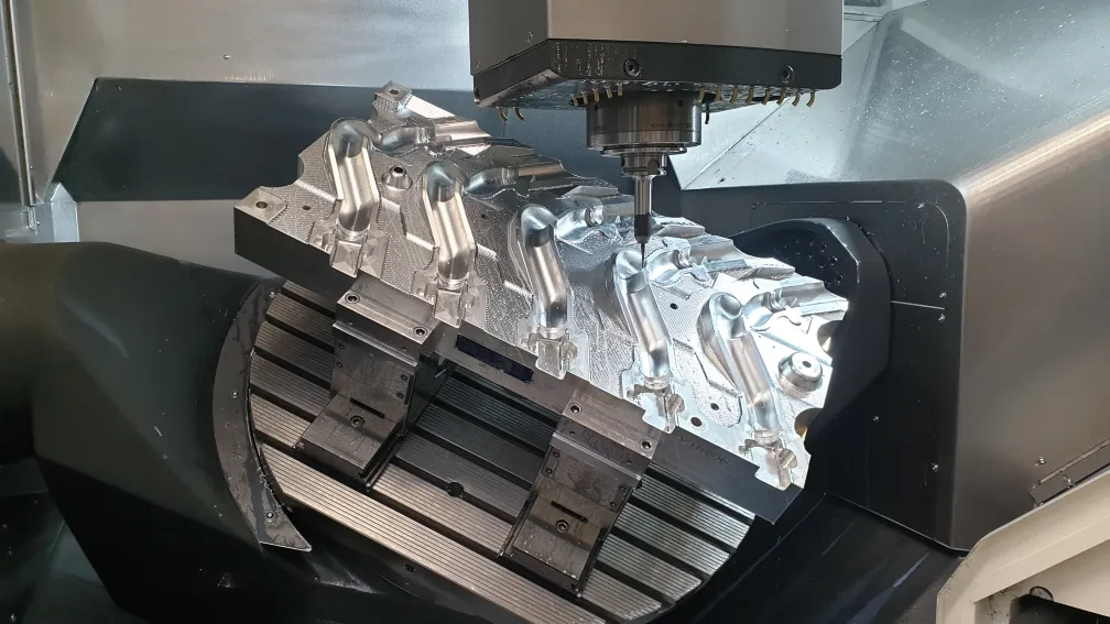 Aluminiumbauteil auf dem geschwenkten Rundtisch, die Spindel fräst im Arbeitsraum
