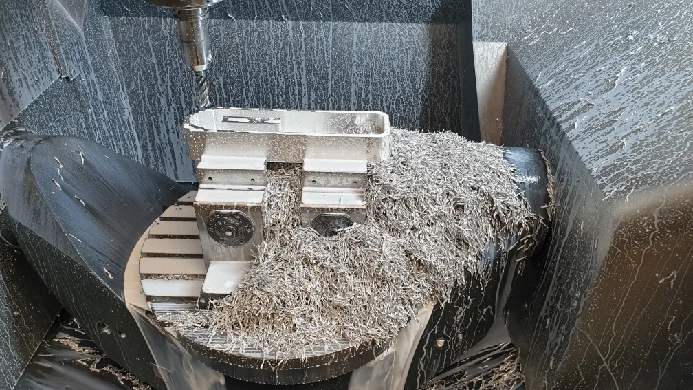Gefrästes Bauteil im Schraubstock, umgeben von Spänen